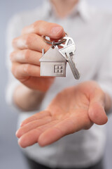 Close-up view of female realtor holds key in her hands. Mortgage. Concept of buying new house.