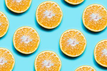 Colorful pattern of cutted orange fruits on background of cyan color.
