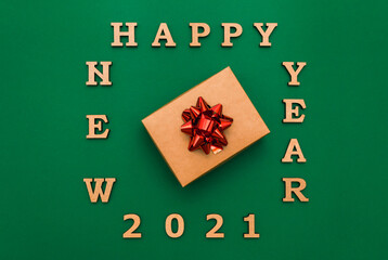 Happy new year 2021 greeting card.Christmas border with craft gift box and red bow on green background. Winter vacation. Place for text. Top view, flat lay. Christmas. Template, banner.