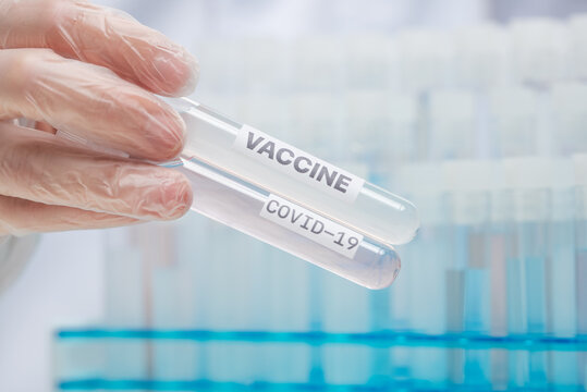 Hand in protective gloves holds biological tubes with covid-19 sample and vaccine example. Study of coronavirus in laboratory. Healthcare and medical concept.