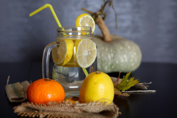 Lemonade in a glass jar with sliced lemon slices and a drinking tube on a decorated wooden desk. Healthy drink concept. Close up, selective focus