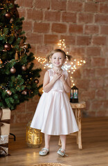 The adorable little girl in gorgeous dress standing near Christmas tree