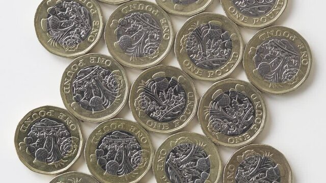 Rotating Reverse Of 2017 British 1 Pound Coins Laid Flat On A White Surface - Top Shot 