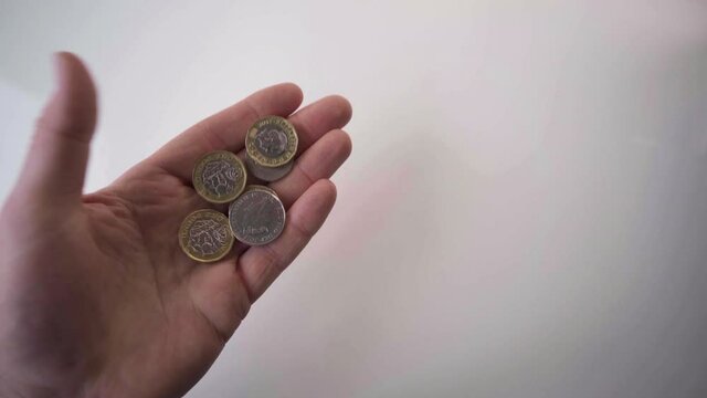 Obverse And Reverse Five Pieces British One Pound Coins In Hand On White Background - High-Angle Shot