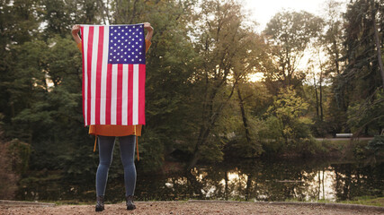 Young woman in the park holding USA flag. High quality photo