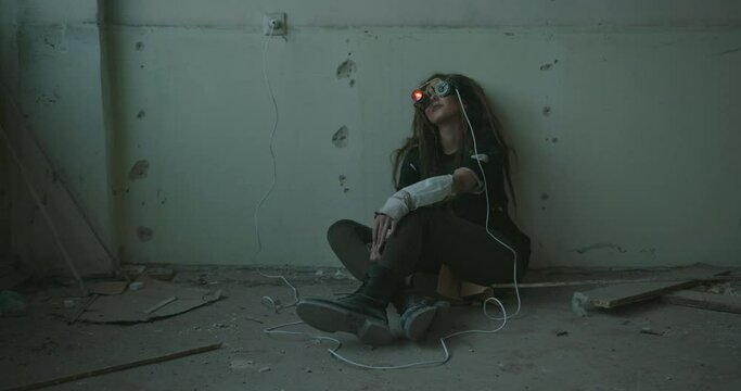 Crazy inventor testing handmade VR glasses. Mad female scientist in dirty clothes sitting in shabby room and testing invented goggles of virtual reality glowing with neon lights