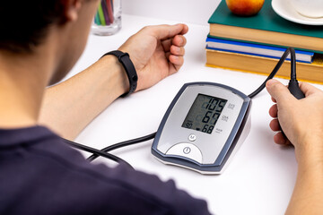 30 years old male person check his blood pressure at home. medical blood pressure measuring electronic device. cardiovascular problem concept