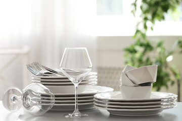 Fototapeta na wymiar Set of clean dishware, cutlery and wineglasses on table indoors