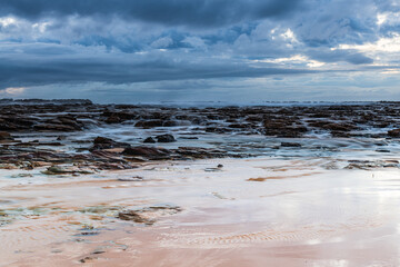 Rock platform, cascades and splashes with rain clouds by the seaside