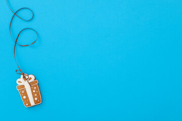 Gift box shaped Christmas cookie on light blue background, top view. Space for text