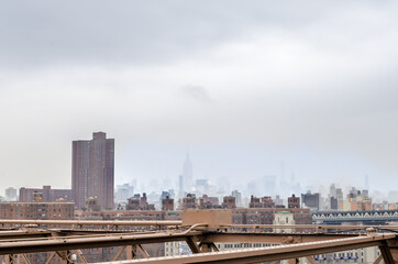 View of New York City, Manhattan from Brooklyn Bridge. Buildings and Skyscrapers Fading Into the Fog