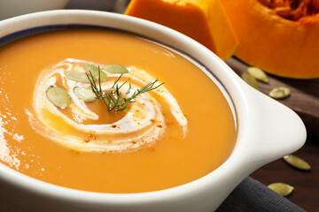 Tasty creamy pumpkin soup with dill and seeds in bowl on table, closeup