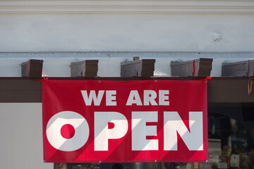 Red and white banner in front of a retail store WE ARE OPEN during the coronavirus covid-19 pandemic