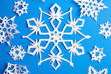 Handmade paper snowflakes on blue background