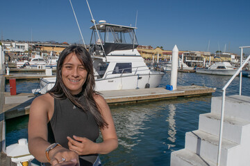 Hispanic Mexican woman showing engagement ring, in front of yacht at sea