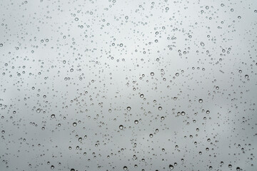 Natural Pattern of raindrops isolated on cloudy background. Rain drops on window glasses surface with cloudy background .