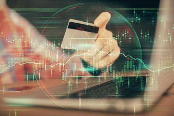 Double exposure of man hands holding a credit card and Forex graph drawing. Stock trading and digital fintech in Internet E-commerce concept.