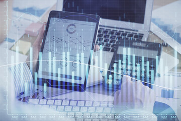 Double exposure of man's hands holding and using a digital device and forex graph drawing. Financial market concept.