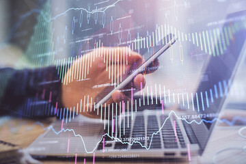 Double exposure of man's hands holding and using a phone and financial graph drawing. Analysis concept.