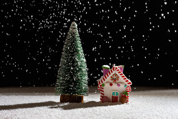 Christmas house and fir tree in a snowing night