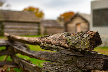 A Wooden Fence With Log Huts Behind It