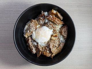 A bowl of grilled yakiniku beef with soft boiled egg on rice.