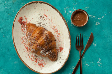 freshly baked croissant with an interesting presentation.
fragrant crispy croissant for breakfast, blue background, unusual serving of the dish