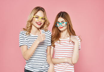 Two women in striped T-shirts trendy glasses communication Friendship together pink background