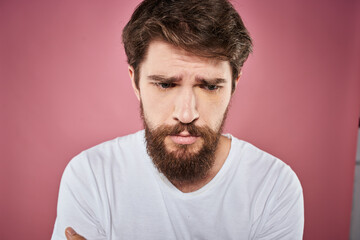 bearded man in white t-shirt emotions displeased facial expression studio pink background