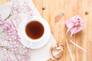 tea cup, gift box and flowers on a wooden background. lifestyle, top view..