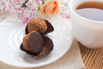two chocolates on a saucer, a cup of tea and flowers. Life style..