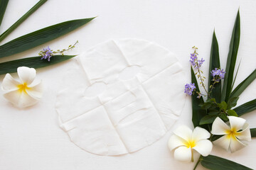 natural cosmetics herbal  sheet mask aroma face mask from bamboo health care for skin face with bamboo leaf ,frangipani ,purple flower decoration flat lay style on background white 
