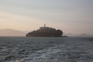 View of Alcatraz Island with prison and lighthouse under sunset in San Francisco, California, USA.