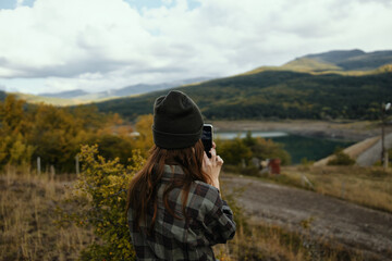 Traveler with a mobile phone in her hands on nature in autumn in the mountains