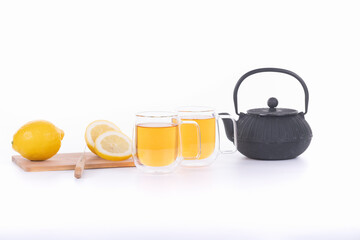 green tea in a transparent cup with a black teapot and lemon