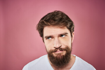 Obraz premium bearded man in white t-shirt emotions displeased facial expression studio pink background