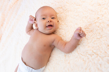 Newborn baby girl in a diaper smiles