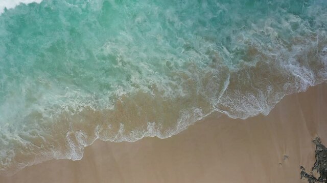 Aerial abstract drone view taken directly from above of impressive tidal waves coming from the Indian Ocean crashing along the shoreline of a rocky beach. The scene was captured in Bali Indonesia.