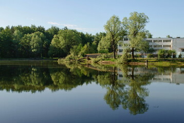 Fototapeta na wymiar Ramenskoe. Moscow region. Russia. June 12. 2017. The school building is reflected in the water of a small pond on a Sunny morning.