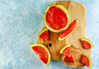 Mini Watermelon with sliced wedges on a light board on a light blue background