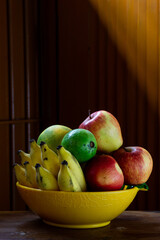 A bowl of fruits with a wooden background