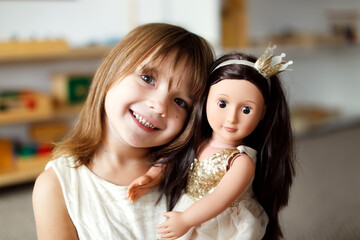 Child girl hugs and plays with a doll, role-playing and story games, delicate colors,