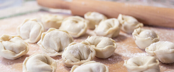 Closeup on semi-finished pelmeni dumplings on the wooden board.