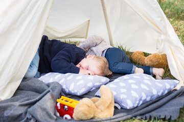 Two little boys - brothers playing in the teepee tent outdoors