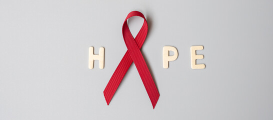 Burgundy Red Ribbon for supporting people living and illness. Healthcare and safe sex concept....