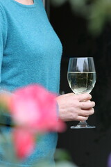 Mature woman holding glass of white wine in garden setting