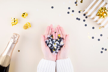Holiday attributes. Woman holding multicolored confetti beige background. Top view