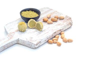 Pistachio matcha white chocolate and candy on a wooden board, on a white background.