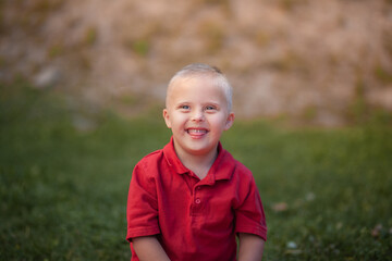 Disabled child, disabled day, boy with Down syndrome in a red T-shirt plays in the park, genetic...