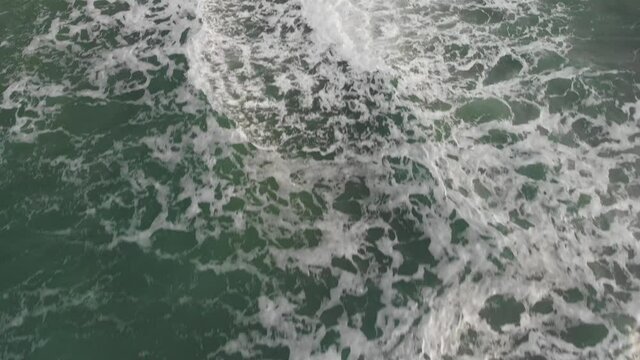 Top aerial view formation of a large ocean waves shows power of nature, the movement of emerald water generates white bubbling foam crests ready to crashing
